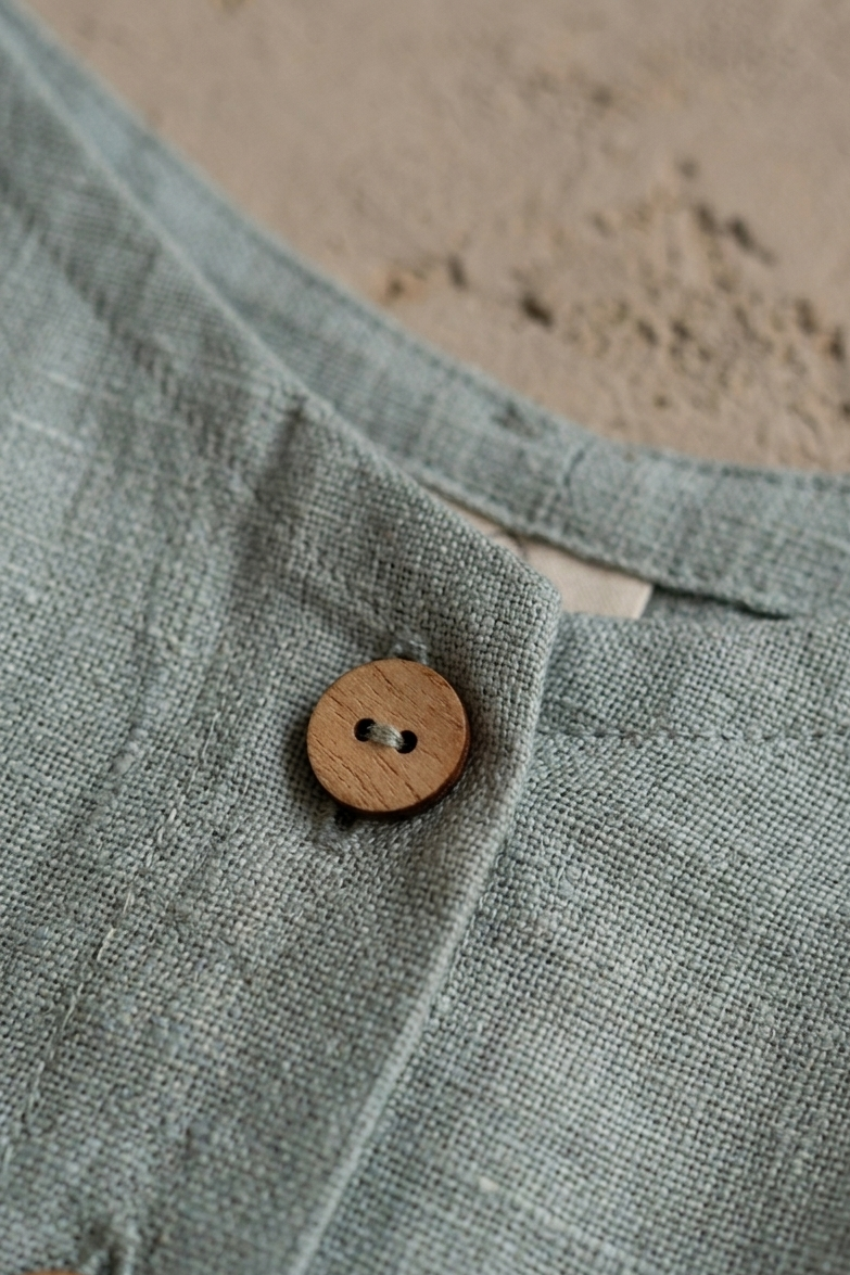 Close-up of a textured fabric with a wooden button on a neutral background